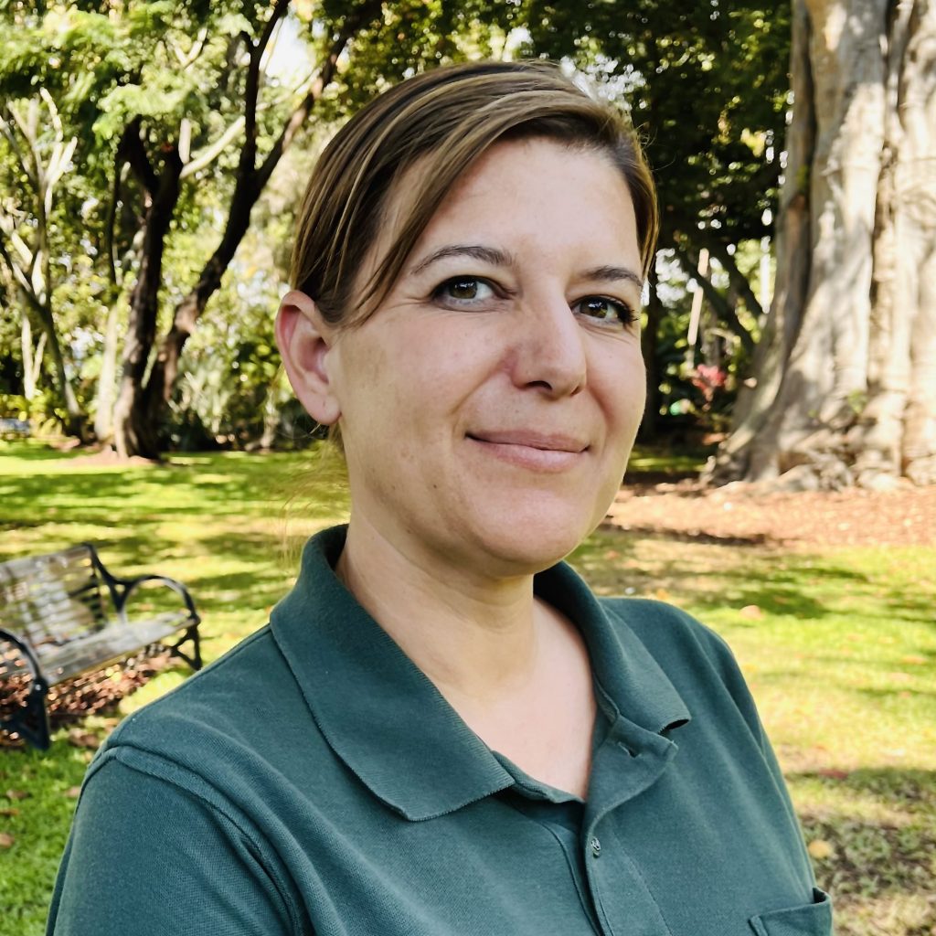 Headshot of Kate Eickstead, the community garden coordinator, with a bench and trees in the background.
