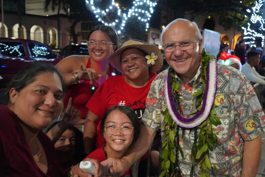 Mayor Rick Blangiardi poses with friends along the Public Worker's Electric Light Parade during Honolulu City Lights