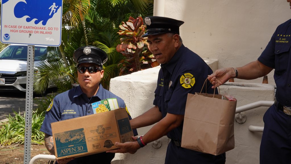 Two firefighters hold boxes of food